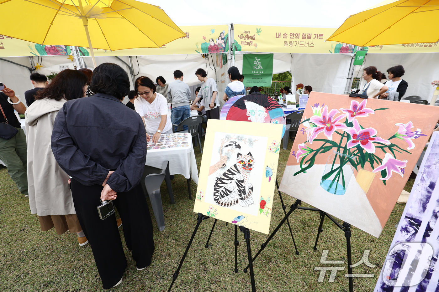 (서울=뉴스1) 김민지 기자 = 11일 서울 용산구 노들섬에서 열린 '2025 서울생활예술페스티벌'에서 시민들이 발달장애인들이 그린 그림을 보고 있다. 2025.10.11/뉴스1