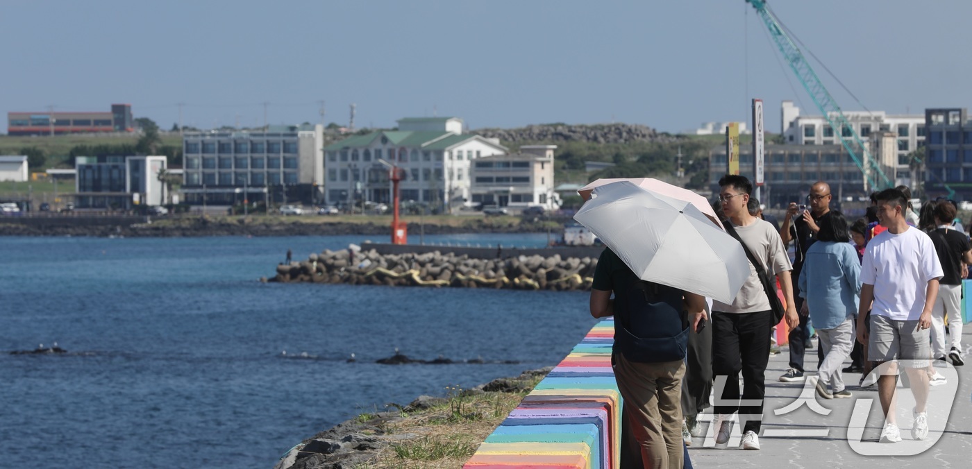 (제주=뉴스1) 고동명 기자 = 12일 오후 제주시 용담 해안도로에서 양산과 반팔 차림을 한 관광객들이 제주의 풍광을 즐기고 있다. 제주는 10월에도 낮 기온이 29~30도의 무더 …