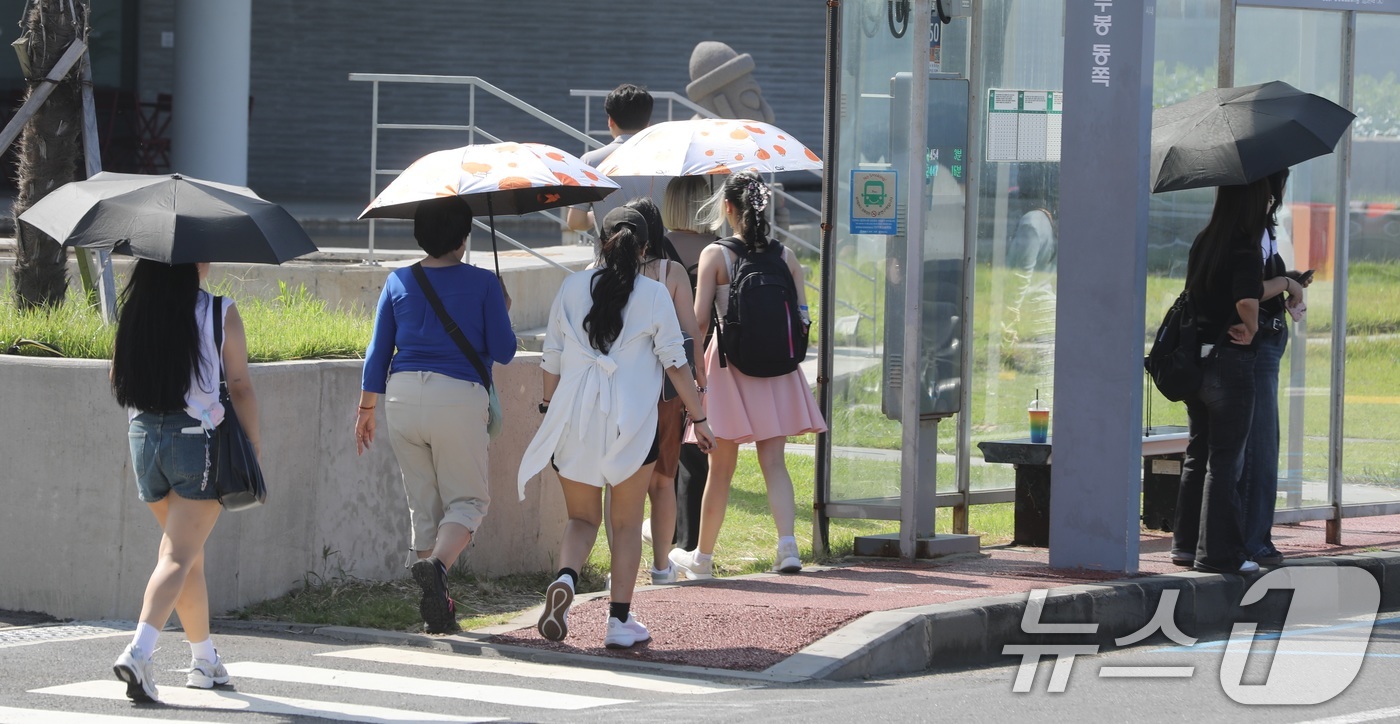 (제주=뉴스1) 고동명 기자 = 12일 오후 제주시 용담 해안도로에서 양산과 반팔 차림을 한 관광객들이 제주의 풍광을 즐기고 있다. 제주는 10월에도 낮 기온이 29~30도의 무더 …