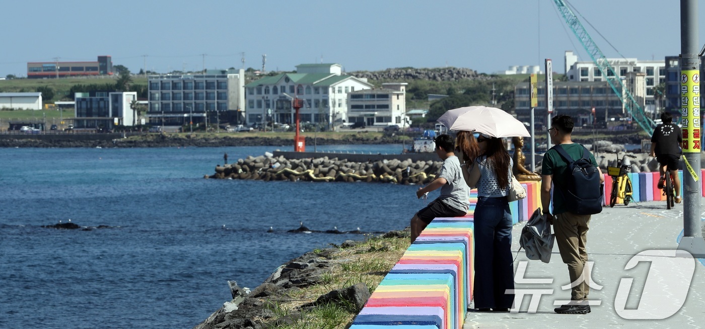(제주=뉴스1) 고동명 기자 = 12일 오후 제주시 용담 해안도로에서 양산과 반팔 차림을 한 관광객들이 제주의 풍광을 즐기고 있다. 제주는 10월에도 낮 기온이 29~30도의 무더 …
