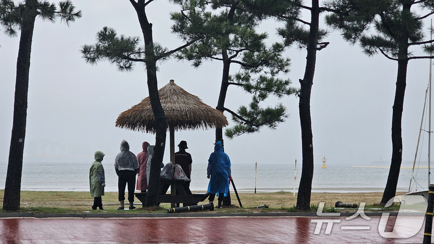 (포항=뉴스1) 최창호 기자 = 13일 경북 포항시 북구 영일대해수욕장 해변에서 시민들이 그늘막 아래에서 비를 피하고 있다. 2025.10.13/뉴스1