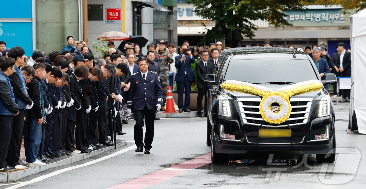 본문 이미지 - 김건희 여사의 각종 의혹을 수사 중인 민중기 특별검사팀의 조사를 받은 후 숨진 양평군 단월면장의 영결식이 열린 14일 경기 양평군청에서 고인의 운구차가 이동하는 가운데 공무원들이 추모 묵념을 하고 있다. 2025.10.14/뉴스1 ⓒ News1 안은나 기자