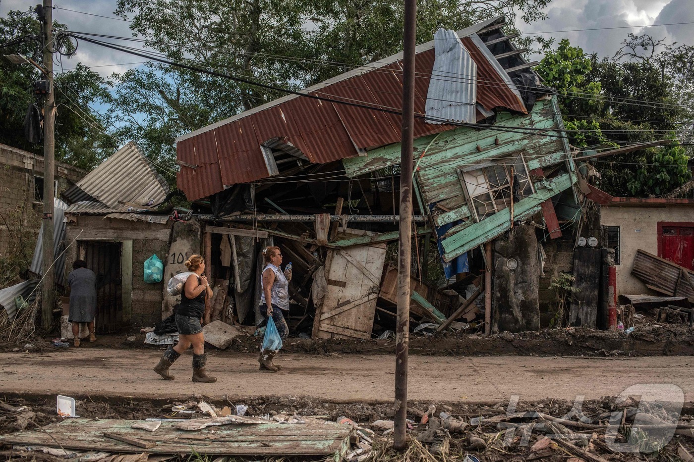 (포사리카 AFP=뉴스1) 권영미 기자 = 14일(현지시간) 멕시코 베라크루스주 포사리카의 라스 그란하스 지역에서 폭우로 피해를 입은 주택 앞을 여성 두 명이 지나가고 있다.202 …