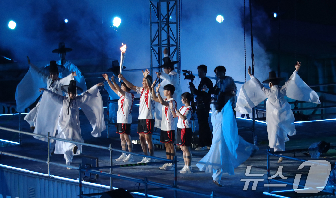 (부산=뉴스1) 윤일지 기자 = 17일 부산 연제구 부산아시아드주경기장에서 열린 제106회 전국체육대회 개회식에서 부산 전통예술의 정수인 동래학춤을 배경으로 성화 주자들이 성화를 …