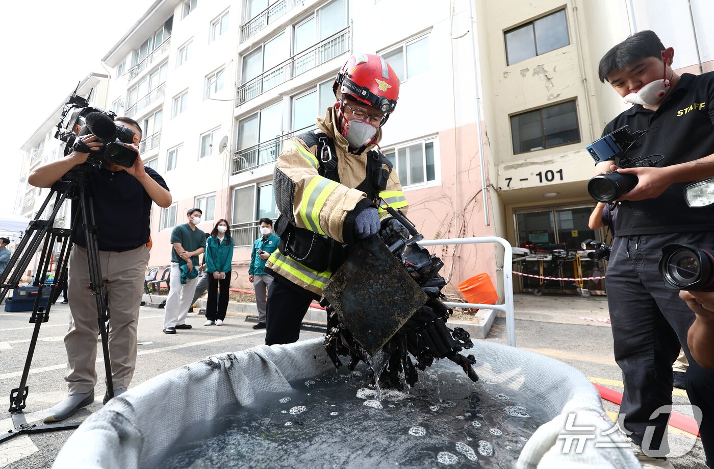 본문 이미지 - 지난 1일 서울 노원구 상계마들아파트에서 열린 &#39;2025 아파트 실험화재 재현실험&#39;에서 서울소방재난본부 소방대원들이 아파트 실내에서 발화를 유도한 리튬이온배터리를 회수해 임시소화수조에 담아 냉각 및 방전시키는 작업을 하고 있다. 2025.10.2/뉴스1 ⓒ News1 김민지 기자