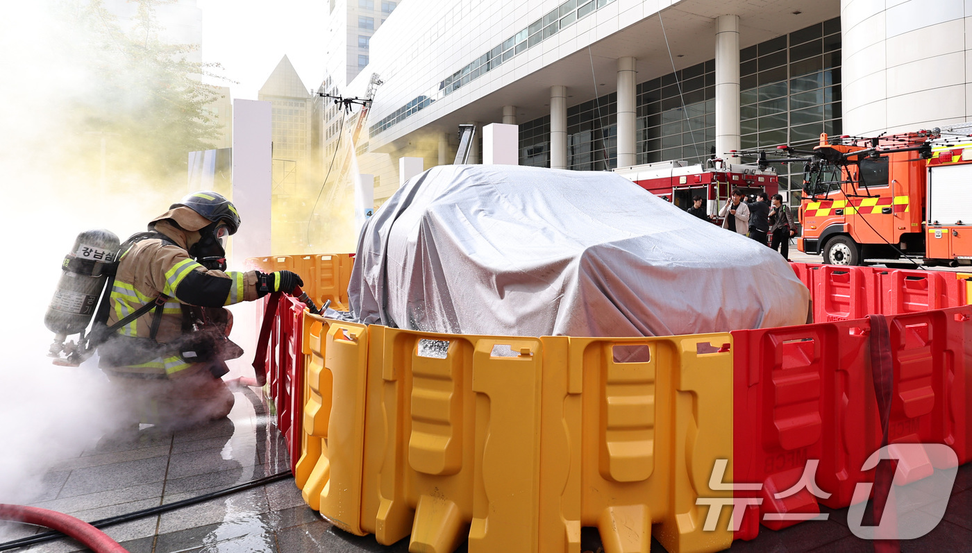 (서울=뉴스1) 구윤성 기자 = 20일 오후 서울 강남구 코엑스에서 열린 '2025 강남구 안전한국훈련'에서 소방대원과 소방드론이 이동식 소화수조에 물을 채워 전기차 화재를 진압하 …