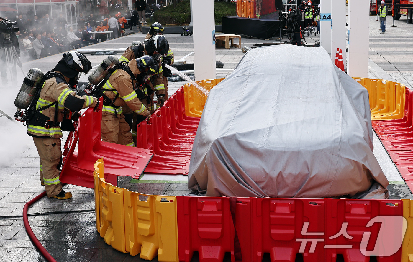 (서울=뉴스1) 구윤성 기자 = 20일 오후 서울 강남구 코엑스에서 열린 '2025 강남구 안전한국훈련'에서 소방대원들이 이동식 소화수조에 물을 채워 전기차 화재를 진압하고 있다. …