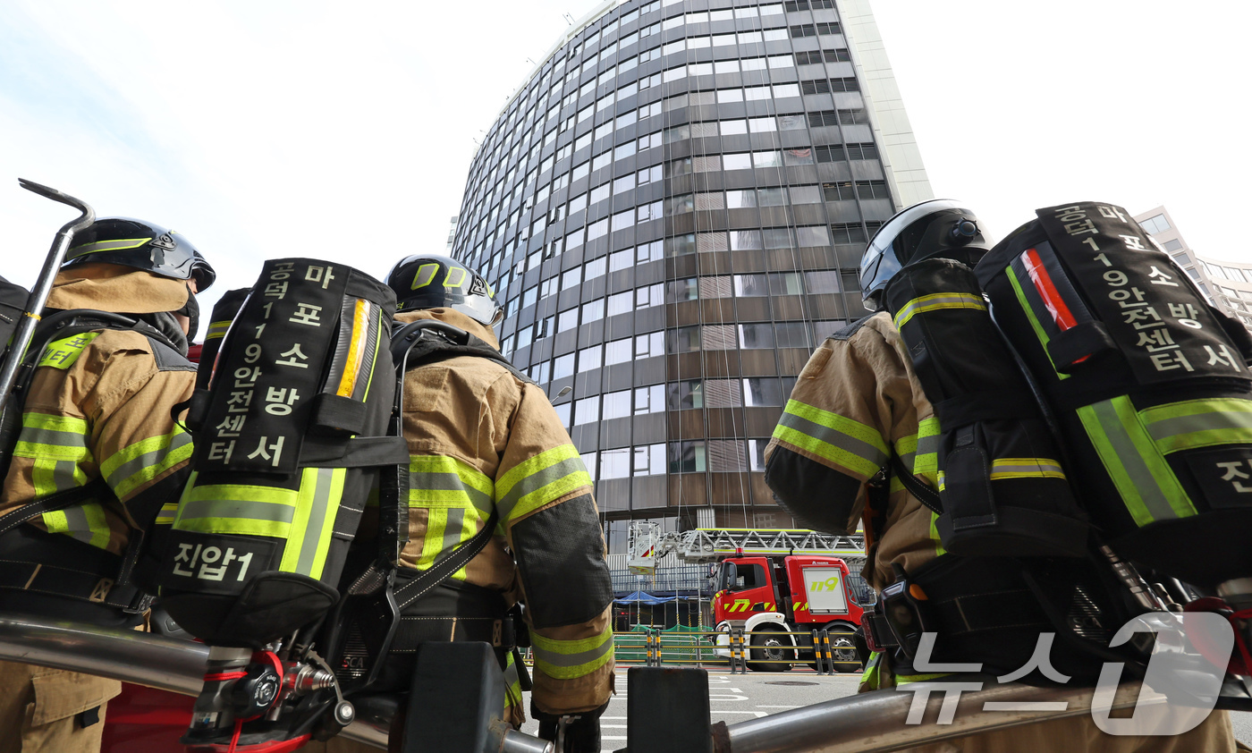 (서울=뉴스1) 장수영 기자 = 21일 오전 서울 중구 서울센터빌딩에서 화재가 발생한 가운데 진화 작업을 마친 소방대원들이 건물을 바라보고 있다.소방당국에 따르면 현재까지 이 불로 …