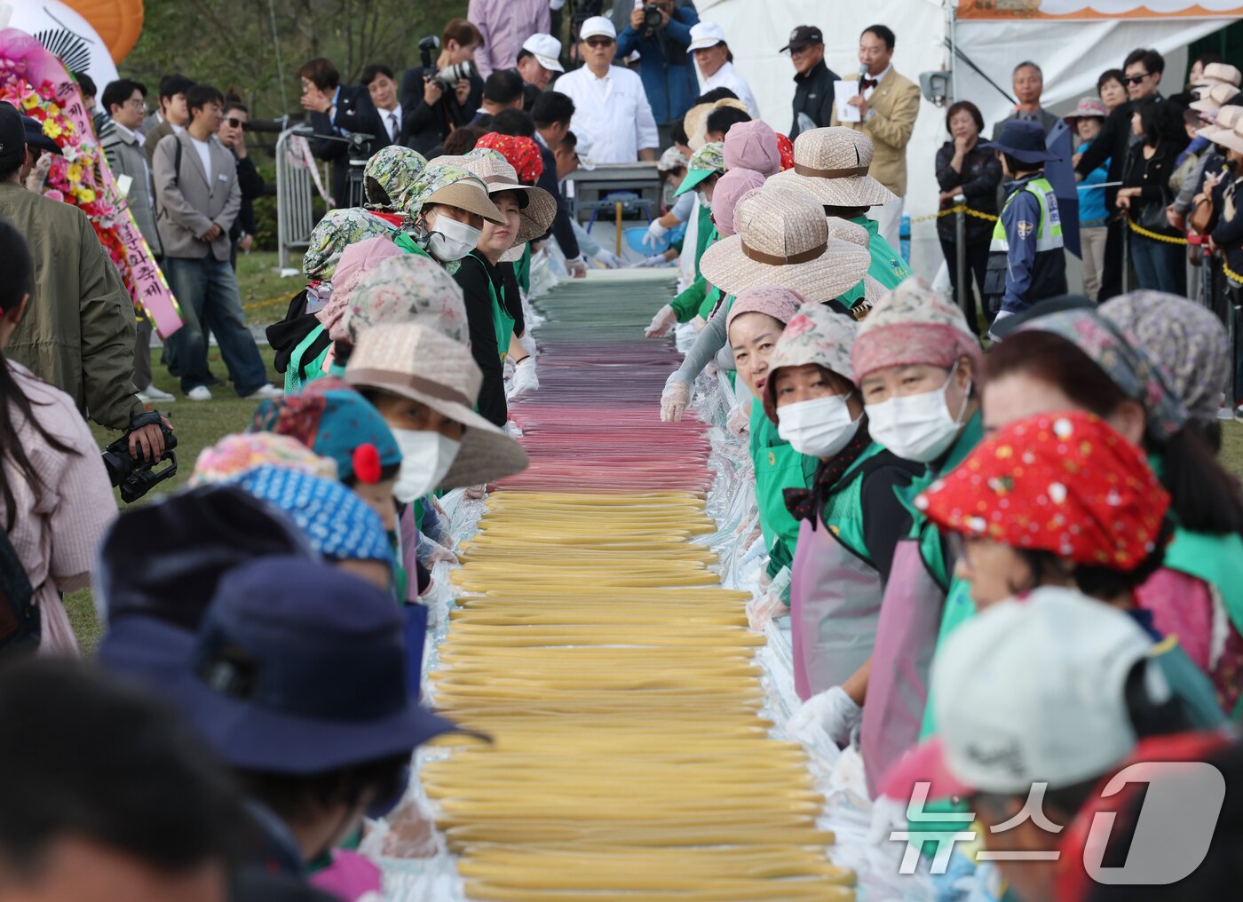 본문 이미지 - ‘제24회 이천쌀문화축제’가 개막한 22일 경기 이천시 모가면 이천농업테마공원에서 행사 관계자들이 600m 가래떡을 만들고 있다. 2025.10.22/뉴스1 ⓒ News1 김영운 기자