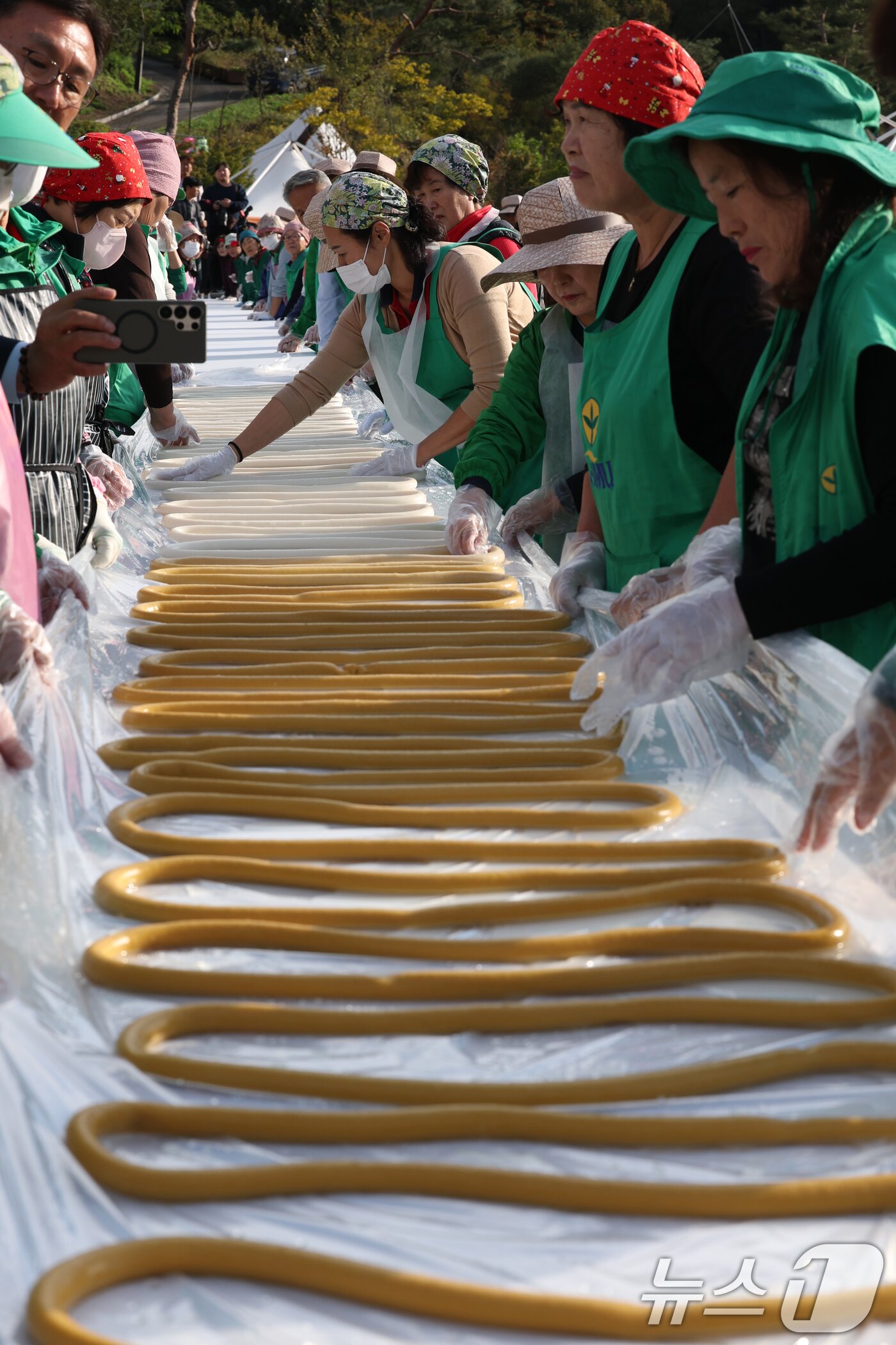 본문 이미지 - ‘제24회 이천쌀문화축제’가 개막한 22일 경기 이천시 모가면 이천농업테마공원에서 행사 관계자들이 600m 가래떡을 만들고 있다. 2025.10.22/뉴스1 ⓒ News1 김영운 기자