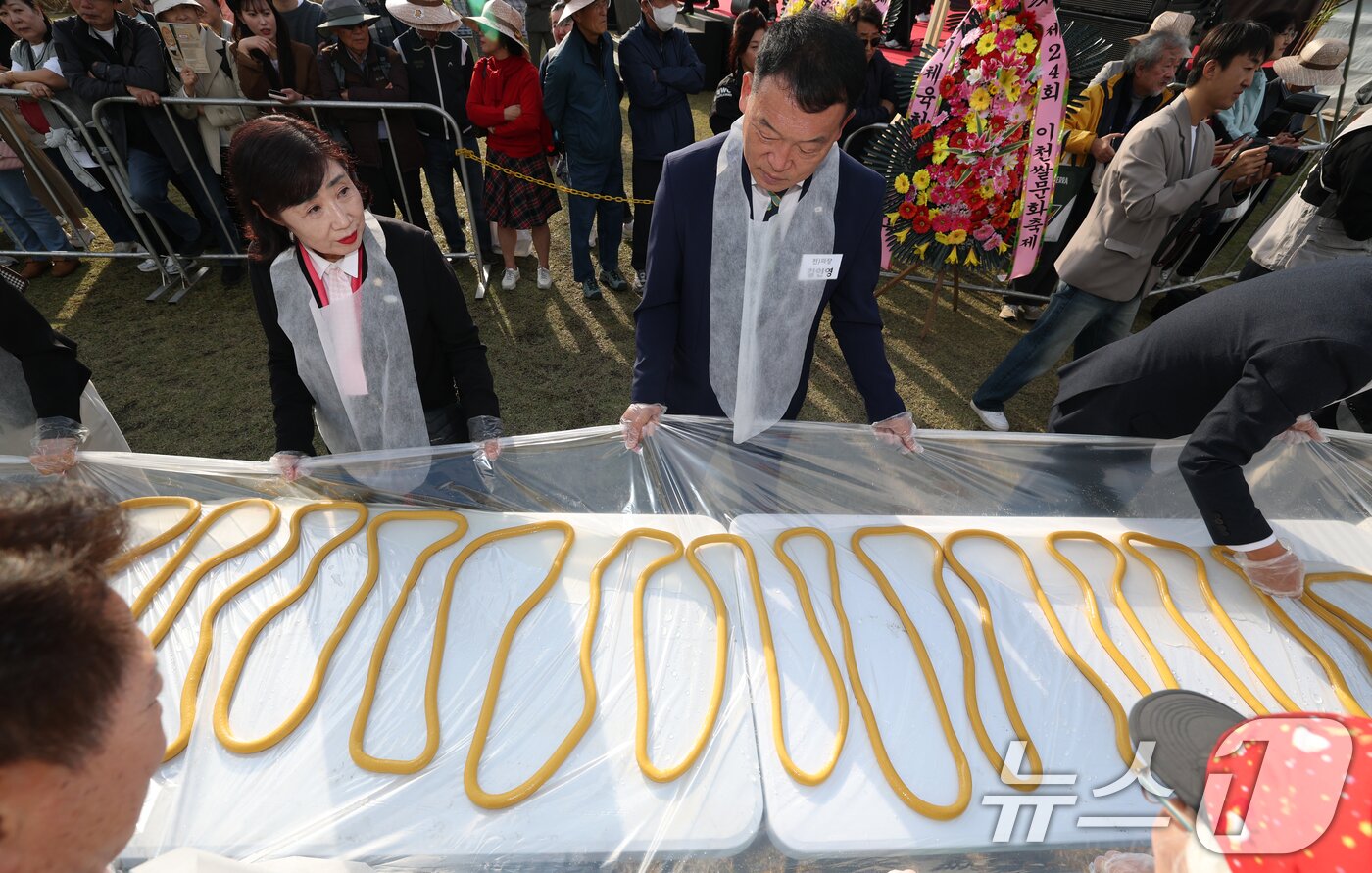 본문 이미지 - ‘제24회 이천쌀문화축제’가 개막한 22일 경기 이천시 모가면 이천농업테마공원에서 행사 관계자들이 600m 가래떡을 만들고 있다. ⓒ News1 김영운 기자