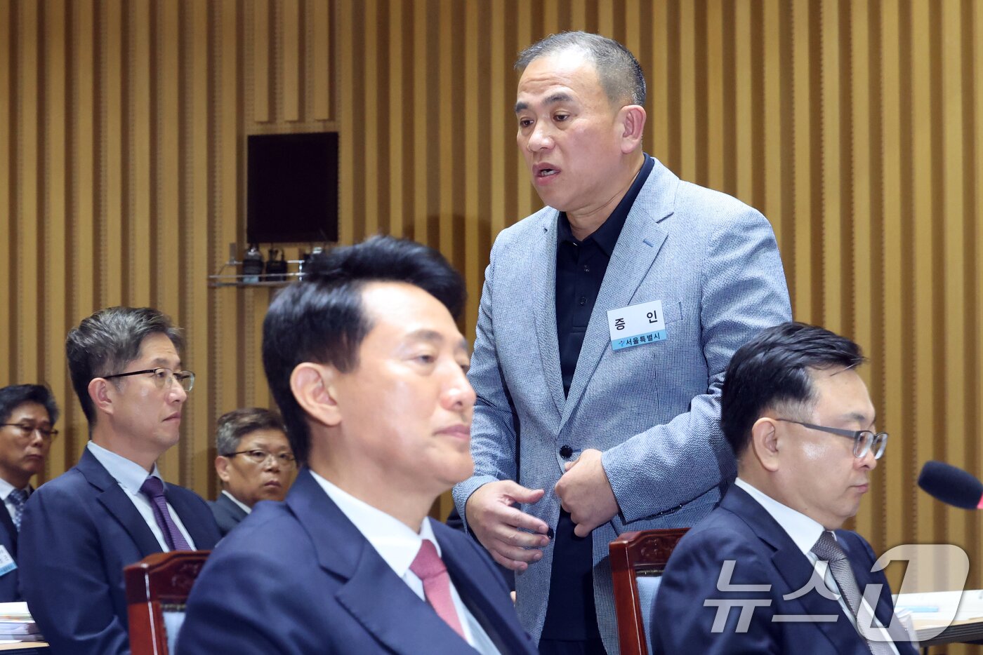 본문 이미지 - &#39;정치 브로커&#39; 명태균씨가 23일 오후 서울 중구 서울시청에서 열린 국회 행정안전위원회 서울시청 국정감사에서 의원질의를 마치고 오세훈 서울시장 뒤로 이동하고 있다. 2025.10.23/뉴스1 ⓒ News1 황기선 기자