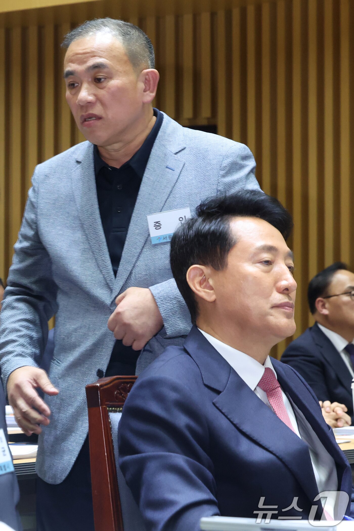 본문 이미지 - &#39;정치 브로커&#39; 명태균씨가 23일 오후 서울 중구 서울시청에서 열린 국회 행정안전위원회 서울시청 국정감사에서 의원질의를 마치고 오세훈 서울시장 뒤로 이동하고 있다. 2025.10.23/뉴스1 ⓒ News1 황기선 기자