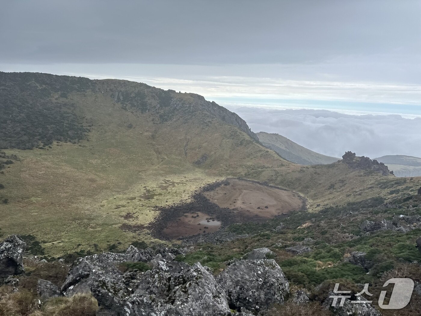 본문 이미지 - 지난 18일 오후 3시 17분께 트랜스제주 100k 대회의 주무대인 한라산 최정상 백록담 풍경. 멀리 구름 사이로 바다도 보인다. 2025.10.18/뉴스1 ⓒ News1 이상휼 기자