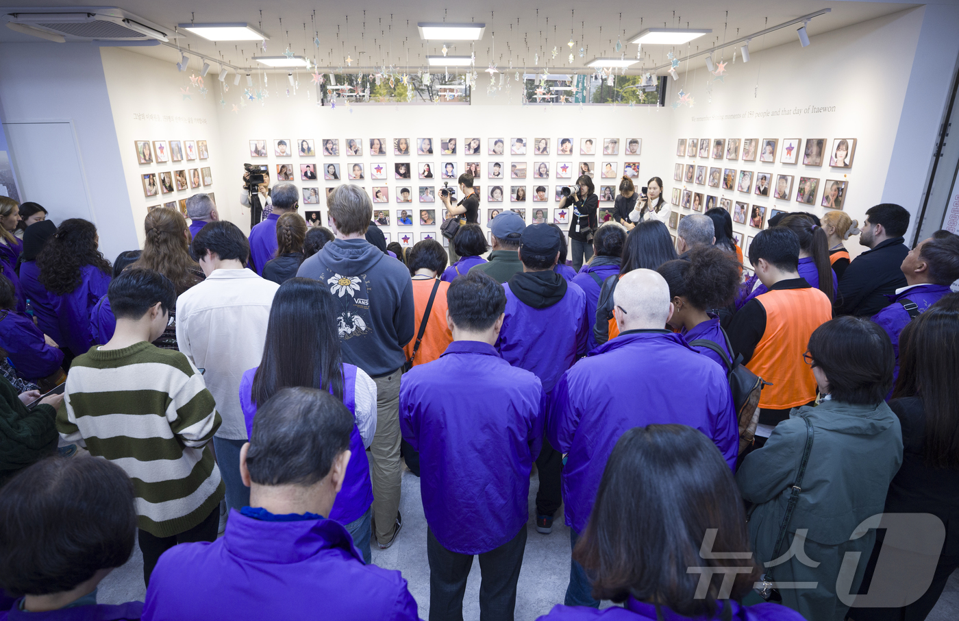 (서울=뉴스1) 김민지 기자 = 26일 오후 서울 종로구 10.29 이태원참사 추모공간 별들의 집에서 열린 외국인 희생자 액자걸기 행사에서 유가족들이 희생자 추모를 위한 묵념을 하 …