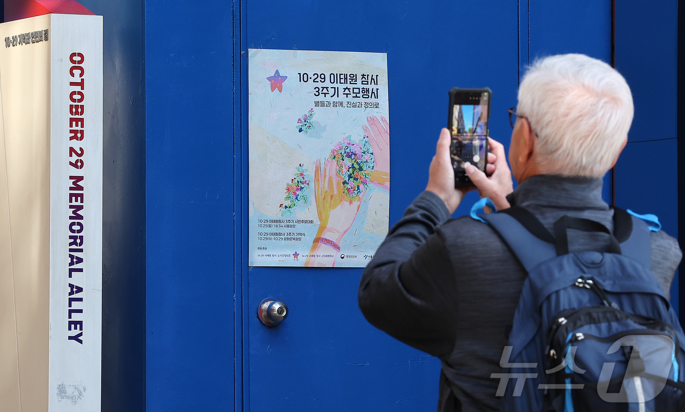 (서울=뉴스1) 김진환 기자 = 10.29 이태원 참사 3주기를 하루 앞둔 28일 서울 용산구 이태원참사 골목에 마련된 추모 게시판을 스마트폰으로 촬영하고 있다. 2025.10.2 …