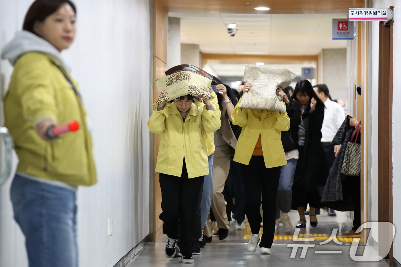 (대구=뉴스1) 공정식 기자 = 28일 오후 대구 달서구청에서 지진 발생 상황을 가정해 열린 대피 훈련에서 구청 직원들이 지진 대피 안내방송에 따라 방석으로 머리를 보호하며 인근 …
