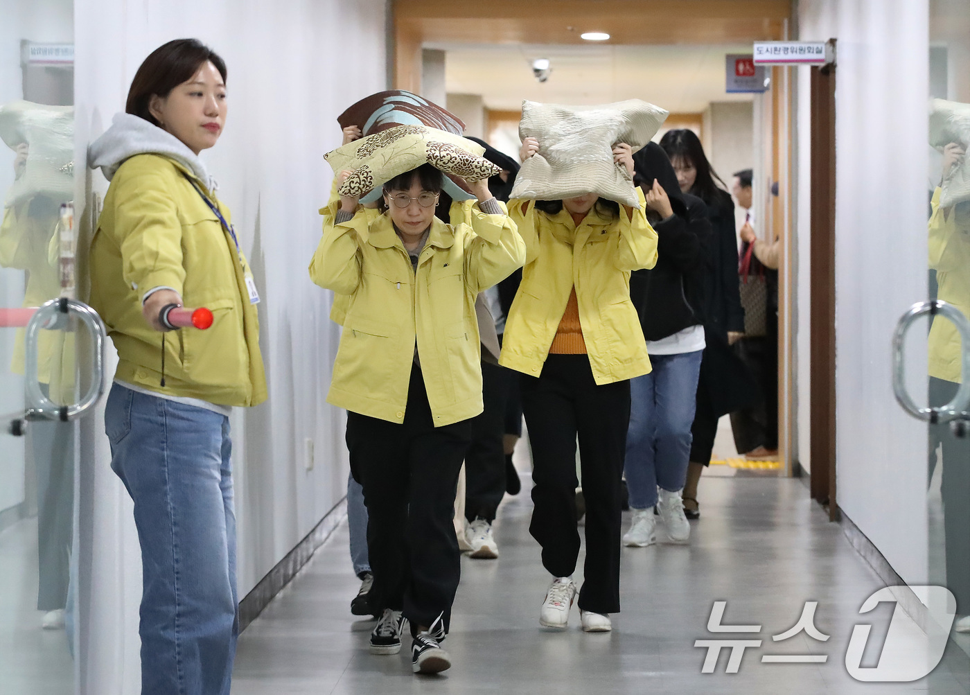 (대구=뉴스1) 공정식 기자 = 28일 오후 대구 달서구청에서 지진 발생 상황을 가정해 열린 대피 훈련에서 구청 직원들이 지진 대피 안내방송에 따라 방석으로 머리를 보호하며 인근 …