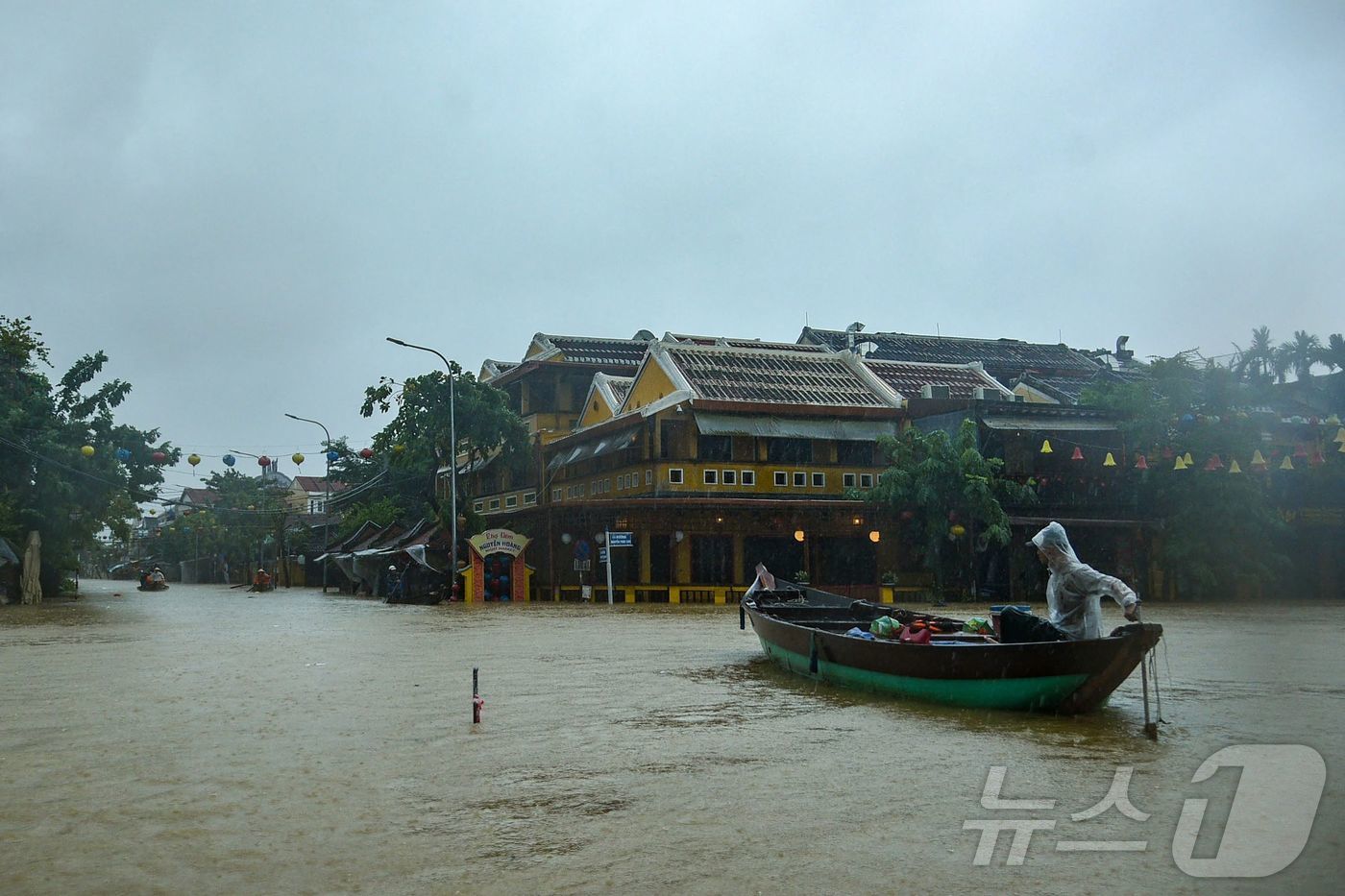 (호이안 AFP=뉴스1) 최종일 선임기자 = 27일 베트남 중부 호이안에서 폭우로 도로가 물에 잠긴 가운데 주민들이 배를 타고 이동하고 있다. 2025.10.27ⓒ AFP=뉴스1