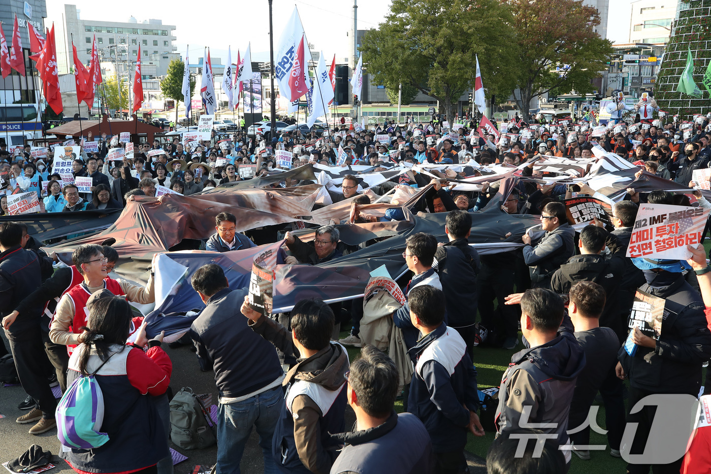 (경주=뉴스1) 공정식 기자 = 29일 오후 경북 경주시 성동동 구 경주역 광장에서 열린 '트럼프 방한 반대 민주노총 결의대회'에서 참석자들이 대미투자 전면철회 등을 주장하며 현수 …