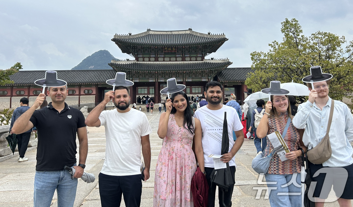 (서울=뉴스1) = 외국인 관광객들이 3일 서울 종로구 경복궁을 찾아 갓 모양 부채 기념품을 들고 기념 촬영을 하고 있다. (국가유산청 제공. 재판매 및 DB 금지) 2025.10 …