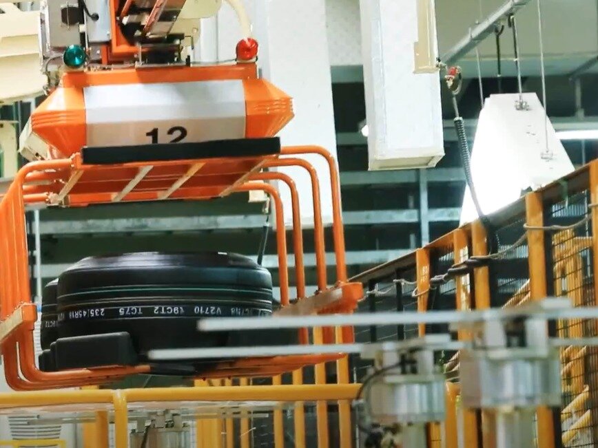 본문 이미지 - 넥센타이어 창녕공장에서 성형 공정을 마친 &#39;그린 타이어&#39;가 &#39;전동화 모노레일 시스템&#39;&#40;EMS&#41;에 실려 운반되는 모습. 모노레일 위 대차는 그린 타이어를 가류 공정 기계까지 자동으로 운반한다&#40;창녕공장 홍보영상 갈무리&#41;. 2025.09.26.