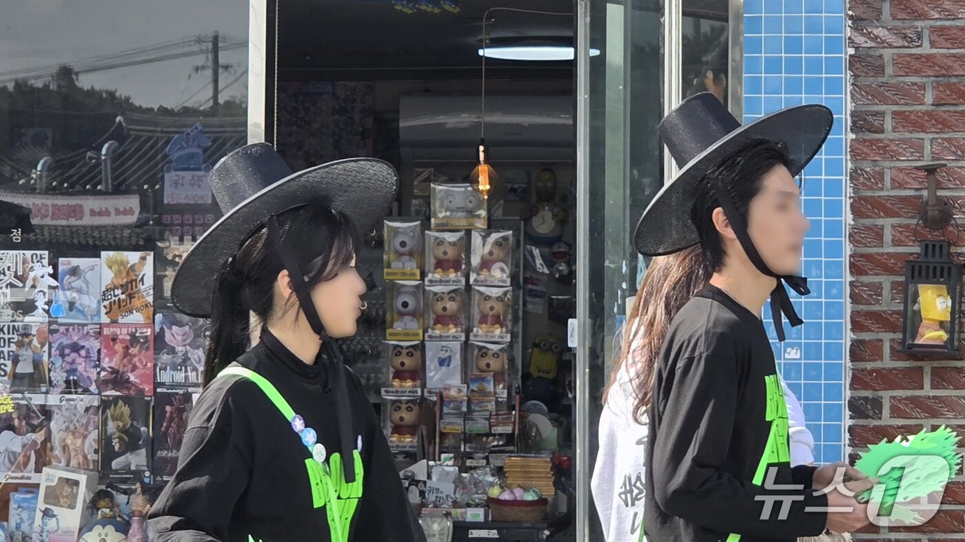 본문 이미지 - 31일 경북 경주 대표 관광지인 황리단길에서 상점 직원이 검은색 갓을 착용한 채 홍보 전단지를 돌리고 있다. 2025.10.31/뉴스1 ⓒ News1 이성덕 기자