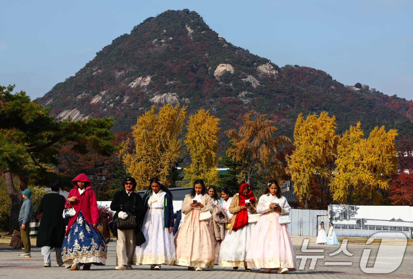 (서울=뉴스1) 김민지 기자 = 포근한 가을 날씨를 보인 11일 서울 종로구 국립고궁박물관에서 한복을 입은 관광객들 뒤로 단풍이 곱게 물들어 있다. 2025.11.11/뉴스1