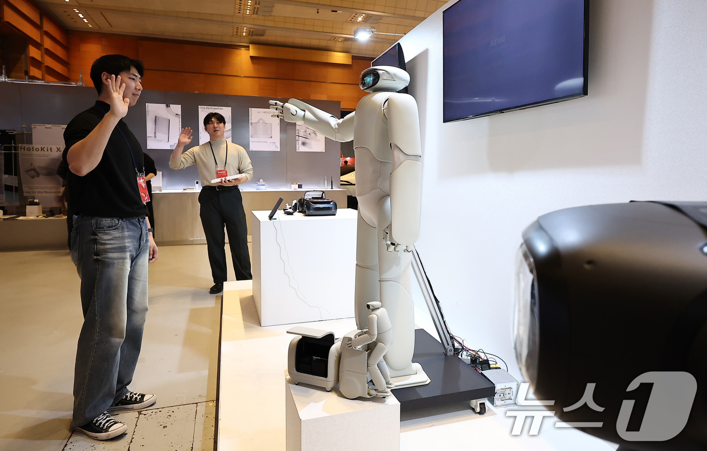 (서울=뉴스1) 김성진 기자 = 12일 서울 강남구 코엑스에서 열린 디자인코리아 2025를 찾은 한 관람객이 홍익대 산업디자인과 제품경험디자인랩 '헤이테이트'가 디자인한 AI휴머노 …