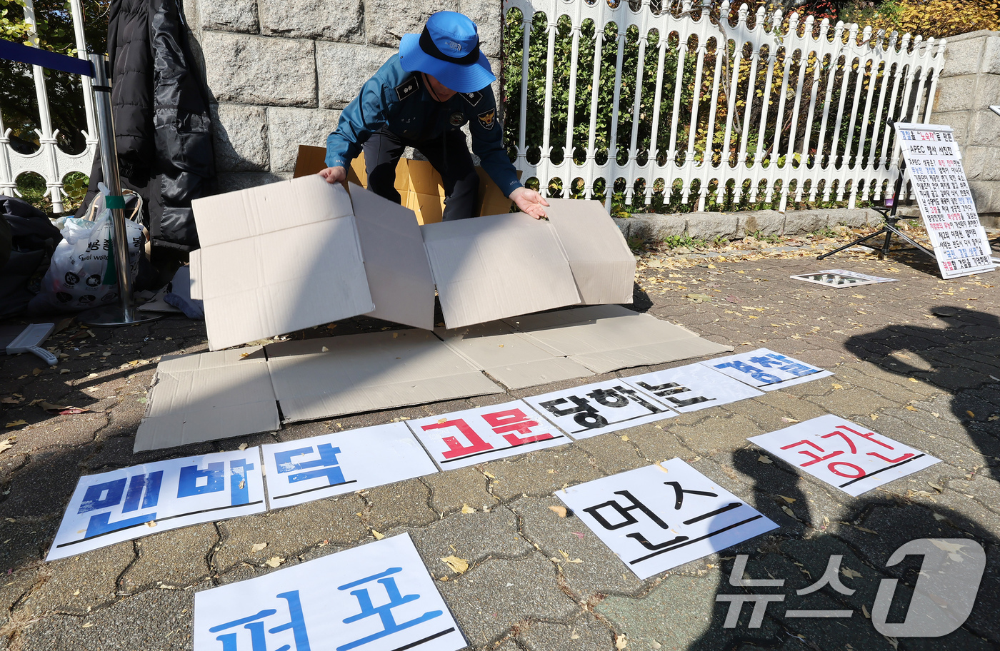 (서울=뉴스1) 장수영 기자 = 12일 오후 서울 여의도 국회 정문에서 열린 경주 APEC 2025 경찰 숙소·식사 실태 비판 사진전에서 관계자가 종이 상자를 바닥에 깔아 놓고 있 …