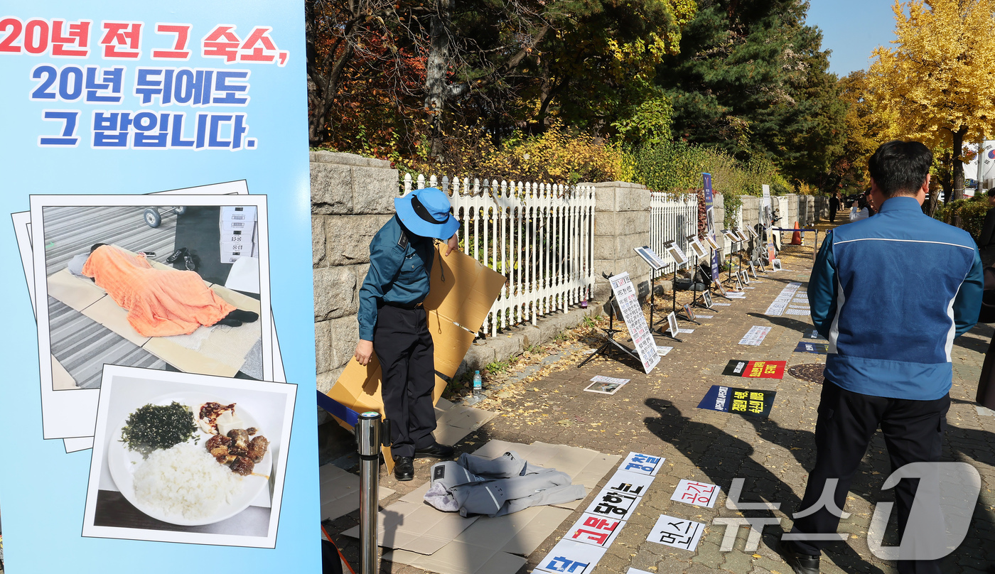 (서울=뉴스1) 장수영 기자 = 12일 오후 서울 여의도 국회 정문에서 열린 경주 APEC 2025 경찰 숙소·식사 실태 비판 사진전에서 관계자가 바닥에 깔아 놓은 종이 상자 위에 …