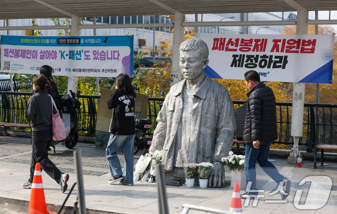 (서울=뉴스1) 안은나 기자 = 전태일 열사 55주기인 13일 서울 종로구 전태일다리에서 한 시민이 전 열사의 동상을 스마트폰에 담고 있다. 2025.11.13/뉴스1