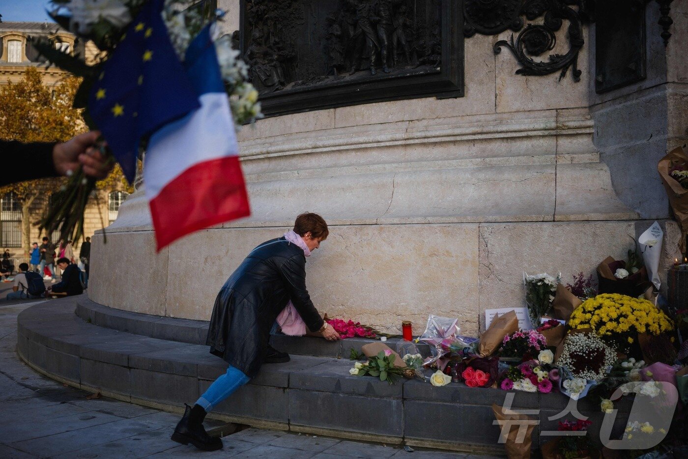 본문 이미지 - 11일&#40;현지시간&#41; 파리 레퓌블리크 광장에 마련된 임시 추모비에서 한 여성이 테러 희생자들을 추모하며 꽃을 헌화하고 있다. 2025.11.11. ⓒ AFP=뉴스1 ⓒ News1 이정환 기자