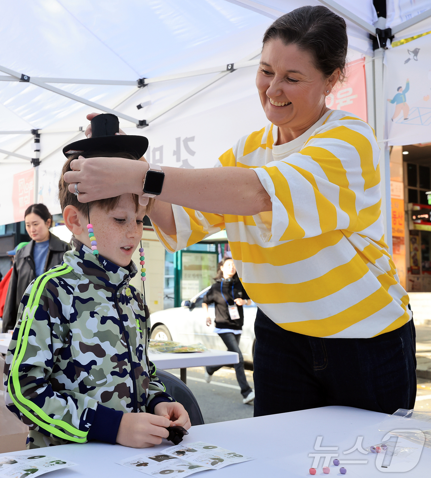 (서울=뉴스1) 김진환 기자 = 15일 오후 서울 종로구 청계천 장통교 일원에서 열린 '2025 육의전 축제'를 찾은 한 외국인 가족이 갓 만들기 체험을 하며 환하게 웃고 있다. …