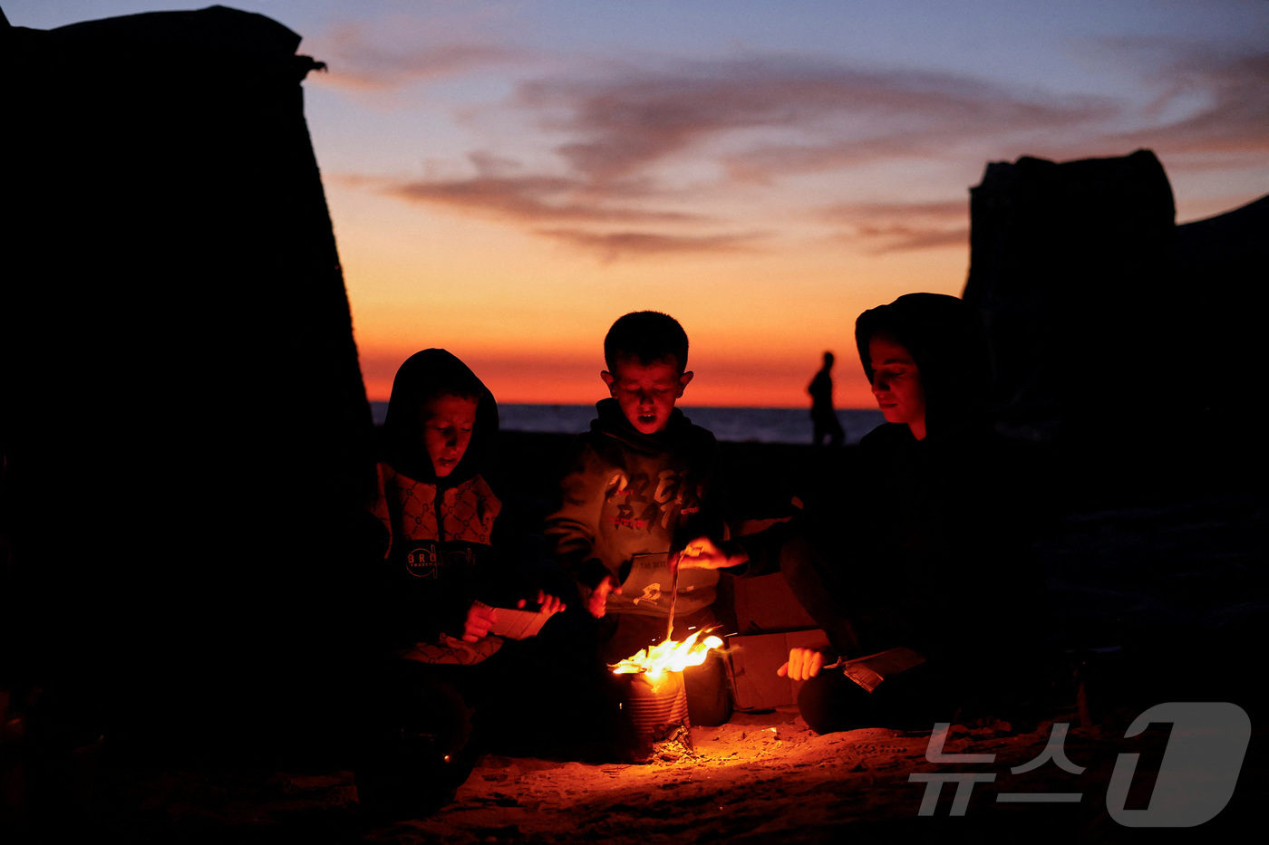 (가자지구 로이터=뉴스1) 윤다정 기자 = 17일(현지시간) 팔레스타인 가자지구에서 어린이들이 모닥불 옆에 앉아 온기를 쬐고 있다. 2025.11.17.ⓒ 로이터=뉴스1