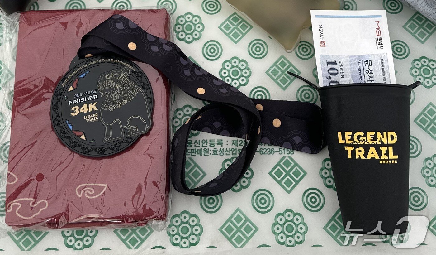 본문 이미지 - &#39;2025 문경 레전드 트레일 백두대간&#39; 트레일러닝 대회 완주 후 제공된 메달과 트레일러닝용 컵, 문경 지역 상품권. ⓒ News1 이상휼 기자