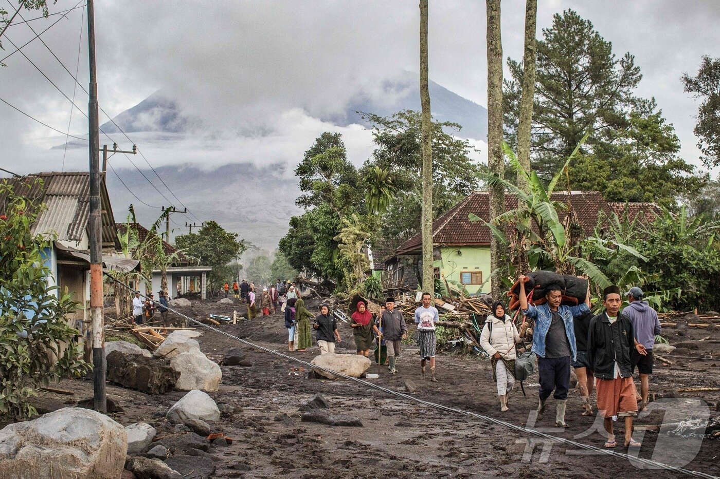 본문 이미지 - 20일&#40;현지시간&#41; 동자바 루마장 수피투랑 마을의 세메루 산이 분화한 다음날 화산재로 덮인 땅을 주민들이 걷고 있다. 2025.11.20. ⓒ AFP=뉴스1 ⓒ News1 이정환 기자
