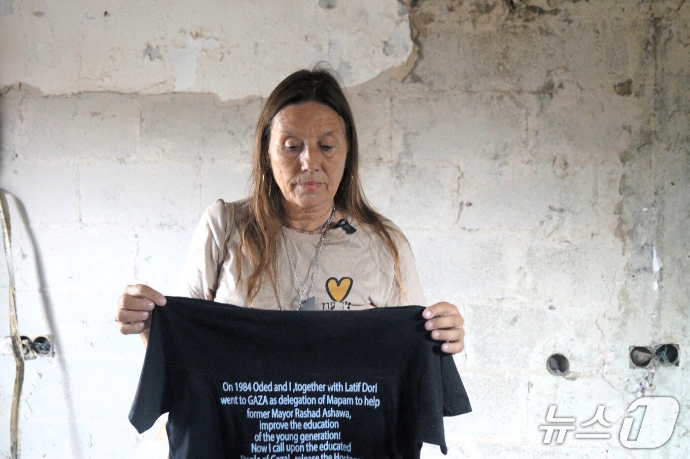 본문 이미지 - 이스라엘 남부 키부츠 니르 오즈에서 주민인 리타 립시츠 씨가 지난 11일&#40;현지시간&#41; 한국 취재진에게 2023년 10월 7일 하마스가 벌인 만행을 상세히 설명했다. 들고 있는 셔츠엔 사망한 시아버지와 사연이 적혀 있다. 2025.11.11 ⓒ 최종일 기자=뉴스1