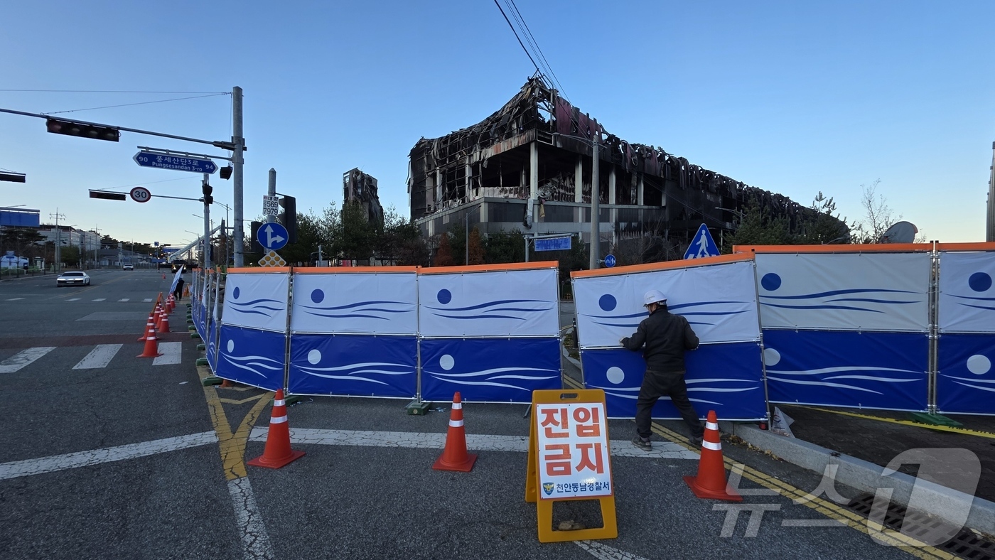 (천안=뉴스1) 이시우 기자 = 이랜드 물류센터 화재 진압이 완료된 21일 충남 천안 동남구 풍세면 이랜드 물류센터 현장 도로에 출입 통제를 위한 안전 펜스가 설치되고 있다.  2 …