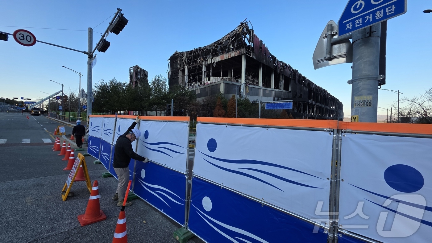 (천안=뉴스1) 이시우 기자 = 이랜드 물류센터 화재 진압이 완료된 21일 충남 천안 동남구 풍세면 이랜드 물류센터 현장 도로에 출입 통제를 위한 안전 펜스가 설치되고 있다.  2 …