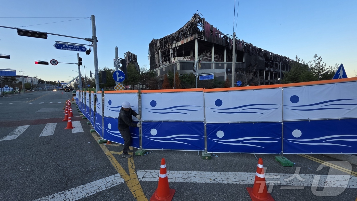 (천안=뉴스1) 이시우 기자 = 이랜드 물류센터 화재 진압이 완료된 21일 충남 천안 동남구 풍세면 이랜드 물류센터 현장 도로에 출입 통제를 위한 안전 펜스가 설치되고 있다.  2 …