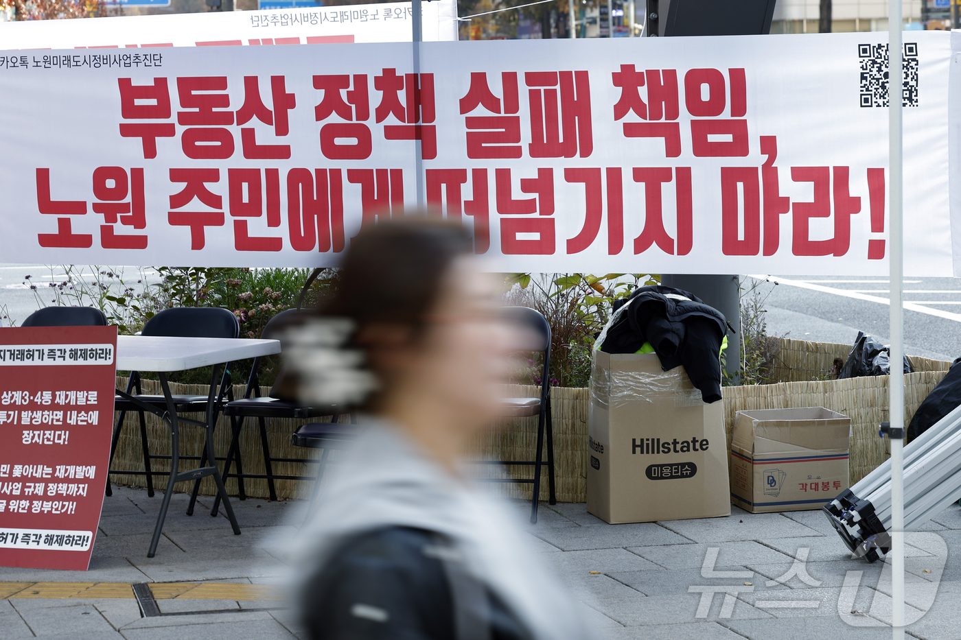 (서울=뉴스1) 박정호 기자 = 22일 오후 서울 노원구 롯데백화점 사거리에 붙은 토허제 규탄 플래카드 앞으로 구민들이 지나고 있다.  2025.11.22/뉴스1