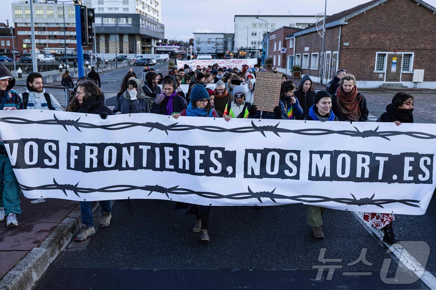 (칼레 AFP=뉴스1) 이정환 기자 = 23일(현지시간) 프랑스 칼레에서 시민들이 '당신들의 국경, 우리의 죽음'이라고 쓰인 현수막을 들고 4년 전인 2021년 11월 24일 도버 …