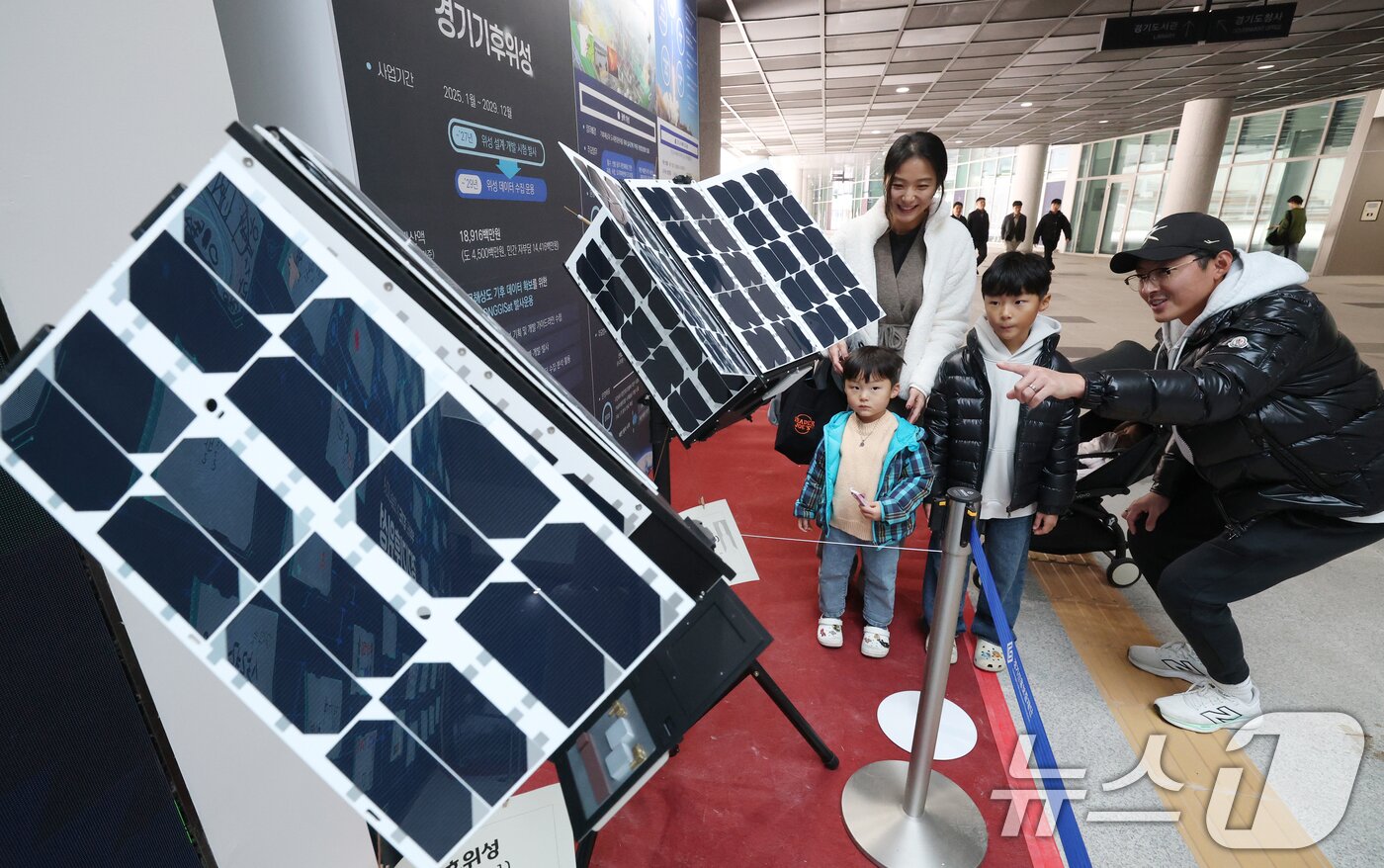 본문 이미지 - ‘경기기후위성’ 1호기 발사를 하루 앞둔 25일 경기 수원시 영통구 경기신용보증재단 도민쉼터에 마련된 경기기후위성 임시상황실에서 시민들이 &#39;경기기후위성&#39; 모형을 살펴보고 있다. ⓒ News1 김영운 기자