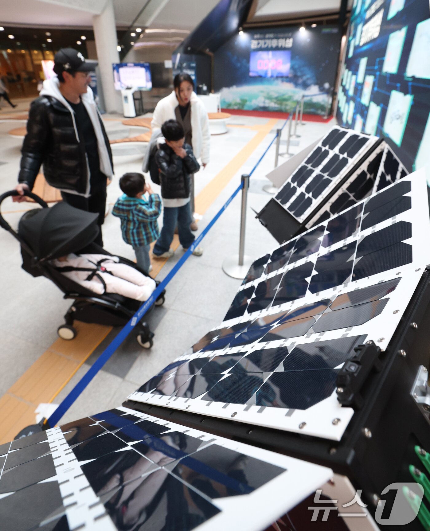 본문 이미지 - ‘경기기후위성’ 1호기 발사를 하루 앞둔 25일 경기 수원시 영통구 경기신용보증재단 도민쉼터에 마련된 경기기후위성 임시상황실에서 시민들이 &#39;경기기후위성&#39; 모형을 살펴보고 있다. ⓒ News1 김영운 기자