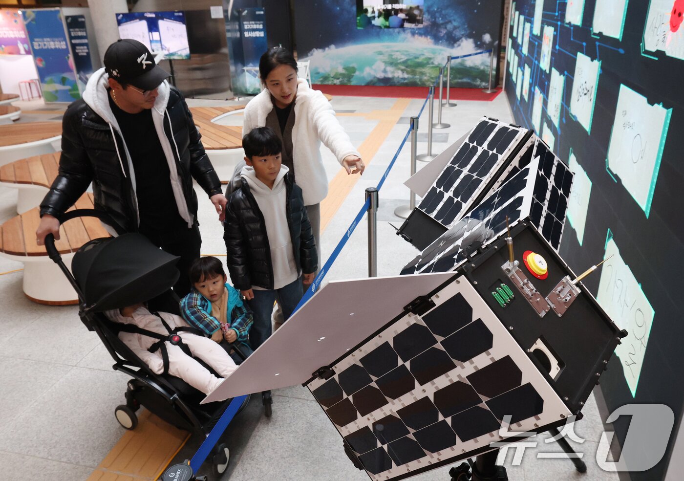 본문 이미지 - ‘경기기후위성’ 1호기 발사를 하루 앞둔 25일 경기 수원시 영통구 경기신용보증재단 도민쉼터에 마련된 경기기후위성 임시상황실에서 시민들이 &#39;경기기후위성&#39; 모형을 살펴보고 있다. ⓒ News1 김영운 기자
