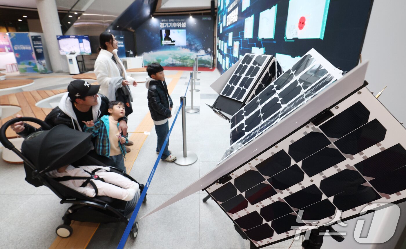 본문 이미지 - ‘경기기후위성’ 1호기 발사를 하루 앞둔 25일 경기 수원시 영통구 경기신용보증재단 도민쉼터에 마련된 경기기후위성 임시상황실에서 시민들이 &#39;경기기후위성&#39; 모형을 살펴보고 있다. ⓒ News1 김영운 기자