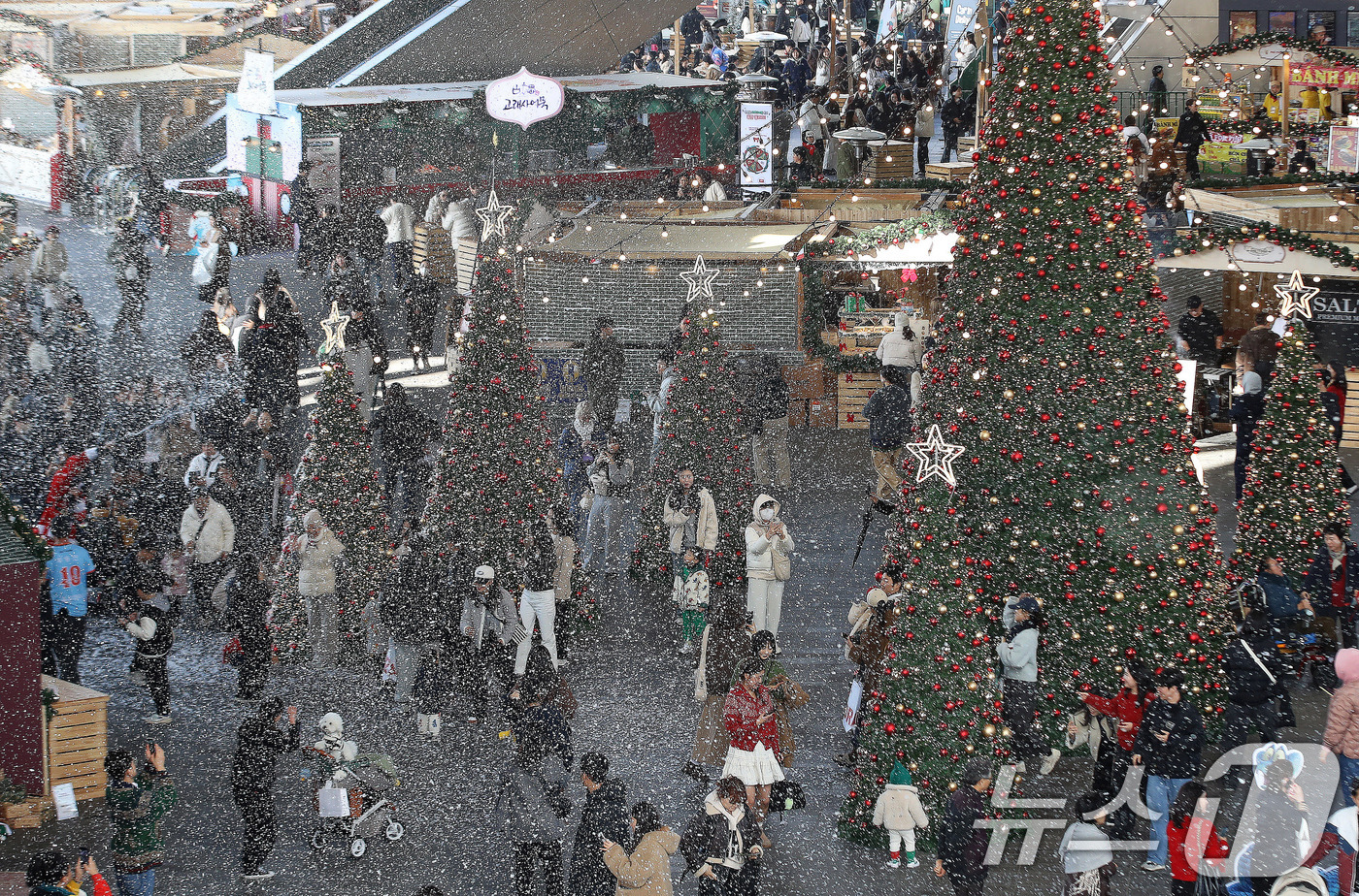 (부산=뉴스1) 윤일지 기자 = 27일 부산 해운대구 영화의전당에서 열린 '크리스마스 빌리지 부산 2025'를 찾은 시민들이 인공눈을 맞으며 크리스마스 트리를 배경으로 사진을 찍는 …