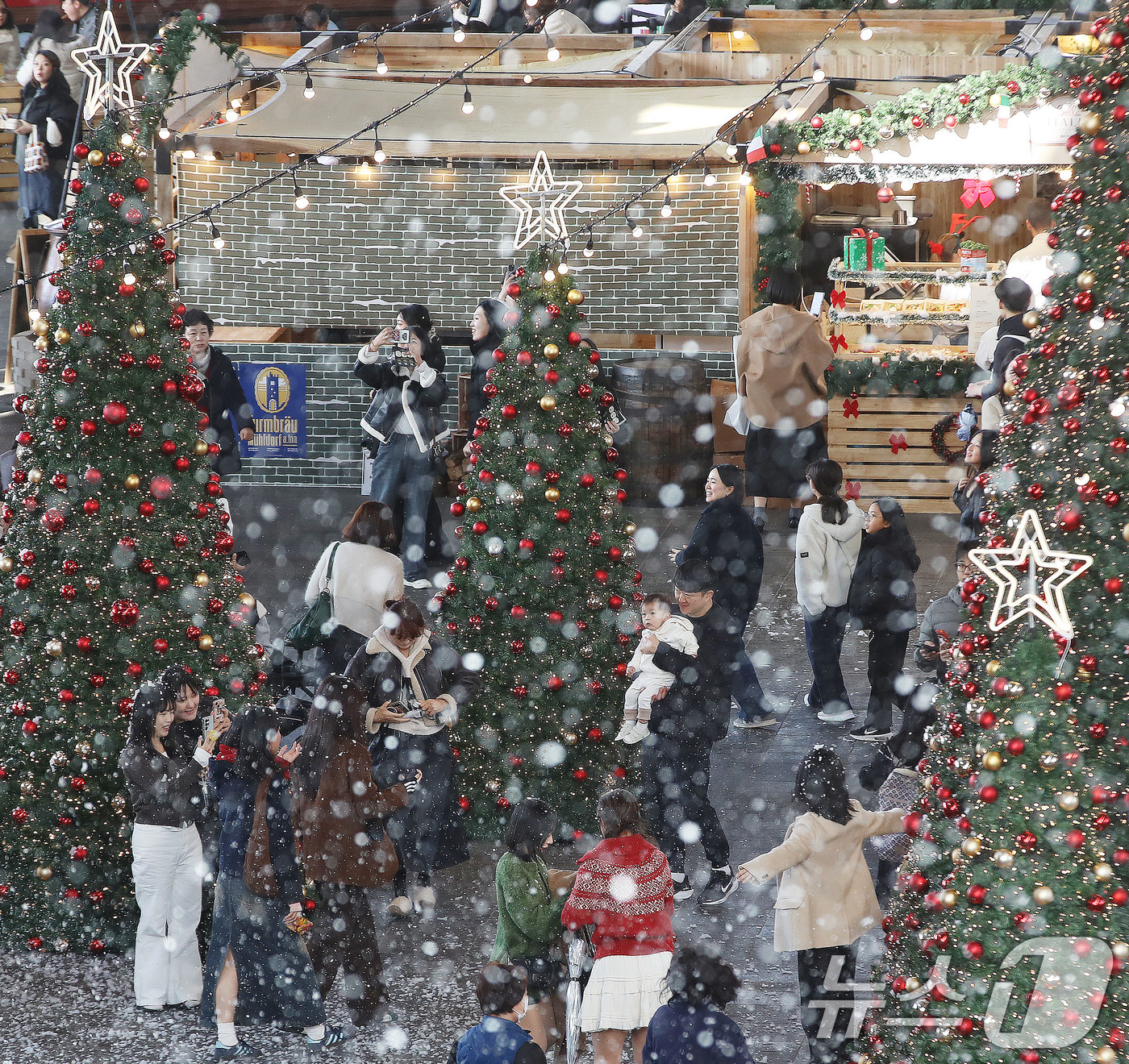 (부산=뉴스1) 윤일지 기자 = 27일 부산 해운대구 영화의전당에서 열린 '크리스마스 빌리지 부산 2025'를 찾은 시민들이 인공눈을 맞으며 크리스마스 트리를 배경으로 사진을 찍는 …