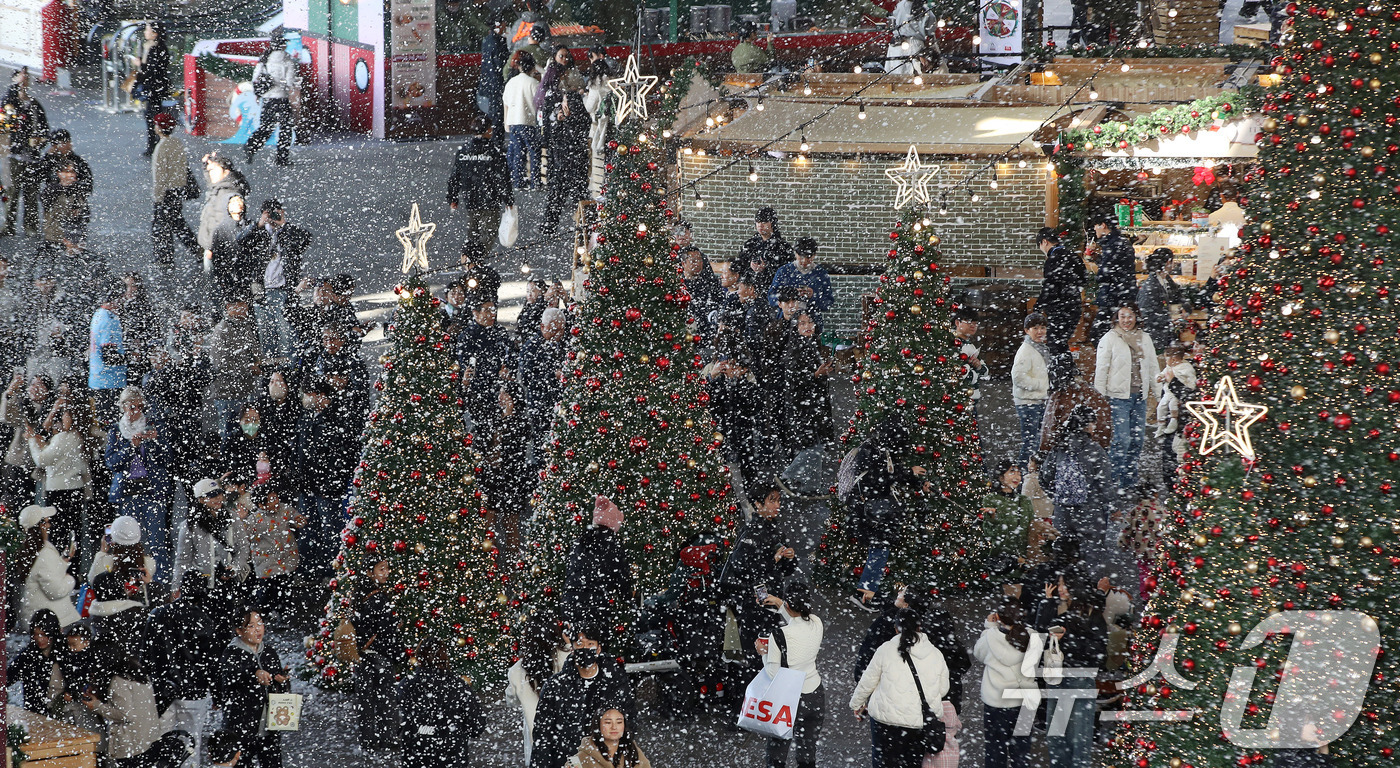 (부산=뉴스1) 윤일지 기자 = 27일 부산 해운대구 영화의전당에서 열린 '크리스마스 빌리지 부산 2025'를 찾은 시민들이 인공눈을 맞으며 크리스마스 트리를 배경으로 사진을 찍는 …